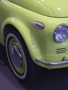 Frontal view of a light green classic car with shiny wheel