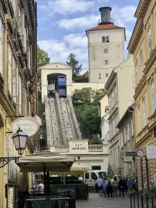 Funicular railway runs in a narrow street surrounded by old buildings and a historic tower