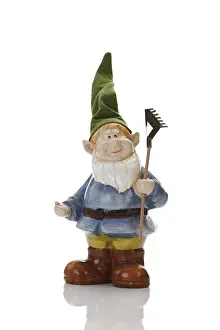 Garden gnome wearing pointed hat holding a rake