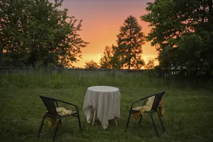 Garden scene with two chairs and a table under a sunset sky