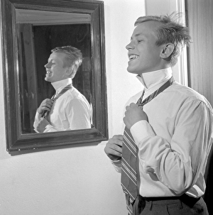 Getting dressed in the 1950s. A young man in front of the mirror knots his necktie