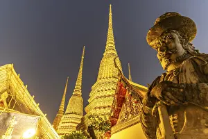 Giant Farang Guard and Chedi of the Buddhist temple Wat Pho at dusk