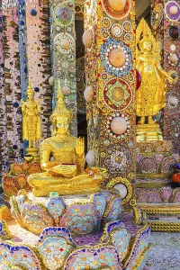 Gilded standing Buddha statues standing on pedestals decorated with mosaics and glass works of art