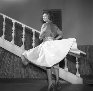 Girl in 1956. The photographer has captured the young woman in motion, her skirt lifting slightly as she moves, a joyful smile lighting up her face
