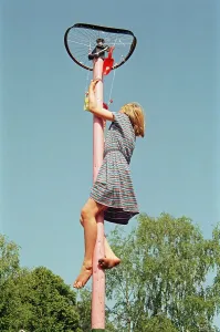 Girl climbing on maypole, barefoot