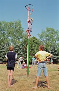 Girl climbing maypole, boys waiting