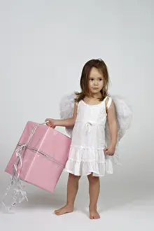 Girl dressed as angel, with Christmas gift