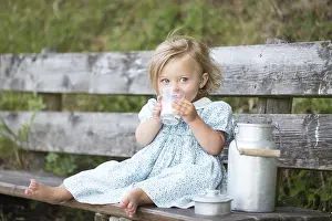 Girl drinking milk on a bench at an Alpine hut