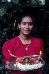 A girl holding oil lamp and flowers on a tray during Onam festival