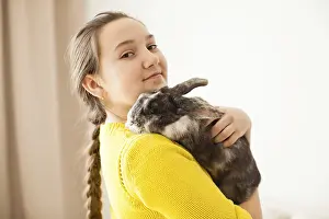 Girl holding a real Lop-eared rabbit and posing with it on camera