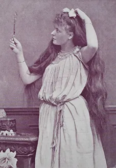 Girl with very long hair looks in a hand mirror