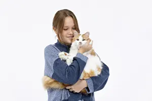 A girl with a radiant smile is hugging her fluffy cat