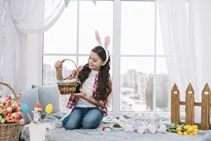 Girl sitting bed looking easter eggs basket home