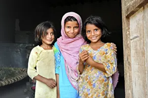 Three girls in the entrance of a simple house