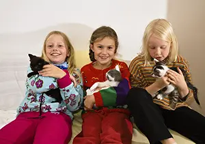 Three girls holding kittens in their arms