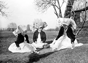 Three girls in traditional costume playing with eggs at Easter