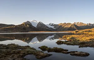 Glaciated mountain peaks reflected in a mountain lake at sunset