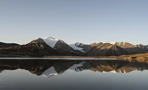 Glaciated mountain peaks reflected in a mountain lake at sunset