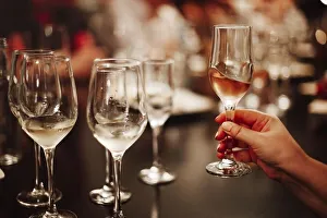 Glasses with different types of wine and human hands holding wine glasses in the background