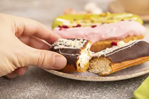 Glazed Eclairs on brown concrete background and green linen textile with hand