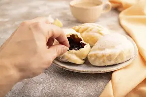 Glazed Pies with blueberry jam on brown concrete background and orange linen textile with hand