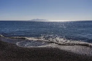 Glittering sea, surf waves on the lava beach of Kamari