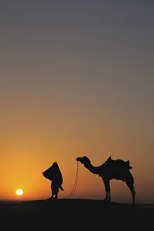 Glorious sunrise man with camel on sand dunes