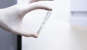 A gloved hand holding a Hantavirus test tube in a sterile lab setting