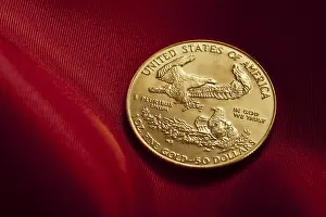Gold coin with eagle design placed on rich red fabric