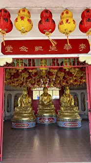 Three golden Buddha statues in the decorative interior of the temple
