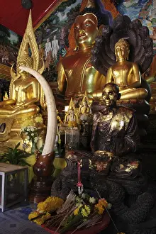 Golden Buddha statues and monk statue with an elephant tusk and sacrifices