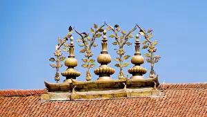 Golden Buddhist ornaments decorate a roof under a blue sky