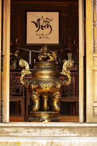Golden incense burner prominently displayed in a traditional temple interior