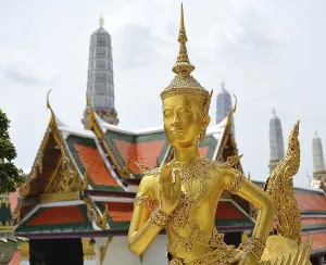 Golden kinnara statue praying with hands joined in a traditional thai greeting