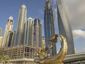 Framed Print : Golden sculpture in front of modern skyscrapers under blue sky