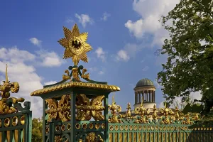 Golden star with black eagle on the fence of Charlottenburg Palace and dome of the Stuler Building
