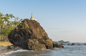 Golden stupa on rock at coastline