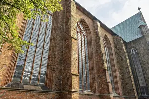 Category Cities DE Prints: Gothic brick church with large stained glass windows and green trees in the foreground