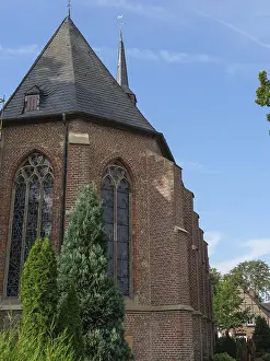A gothic brick church with ornate windows against a clear blue sky