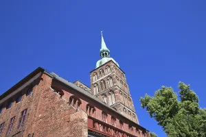 Framed Print : Gothic brick church tower against a clear blue sky next to green trees