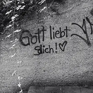 Graffiti with the inscription God loves (s) you and a heart symbol on an outdoor wall