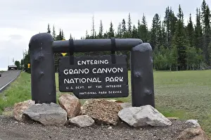 Grand Canyon National Park entrance sign surrounded by trees and stones