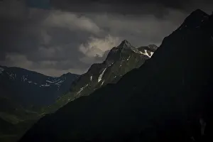 Grassy summit with remnants of snow and dramatic clouds