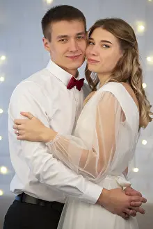On a gray background, the bride and groom look at each other