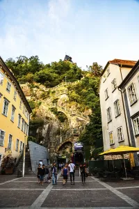 Graz, Austria, 17.08.2019 : View at clock tower from street near steps over the hill