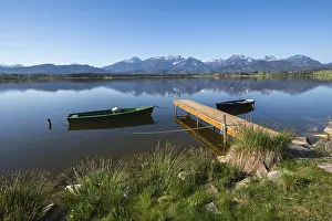 Green and black boat mooring on a quiet lake with Alpine peaks in the background