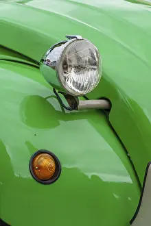 Green bodywork of a vintage car with a striking headlight design
