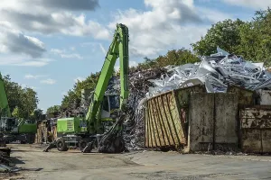 Two green excavators working on the scrap mountain