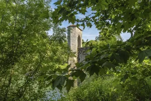 Green leaves frame a medieval bridge tower in sauveterre de bearn