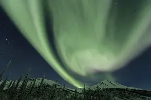 Green Northern Lights (Aurora borealis) over snowy mountains